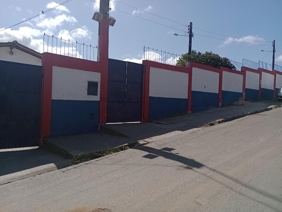 Foto do muro da escola, que é pintado das cores vermelho, branco e azul 