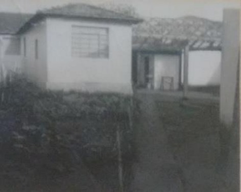 Imagem mostra a entrada do Instituto em preto em preto e branco, ao lado esquerdo possui um mato alto e um caminho que leva a entrada do prédio.