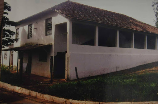 Imagem da Escola Dona Alexandra Pedreiro, mostra um prédio simples, na cor branca e em volta um gramado. 