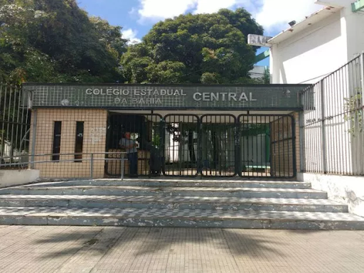 Fachada principal do Colégio Estadual da Bahia. Paredes cinzas e bege, azulejada, com um letreiro metálico e portões de grades pretas. 